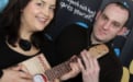 Ruth Jones plays a library book ukulele while Stuart Boydell looks on